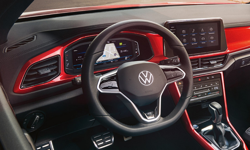View of the cockpit of the red T-Roc Cabriolet with the multifunction steering wheel, radio and digital cockpit.