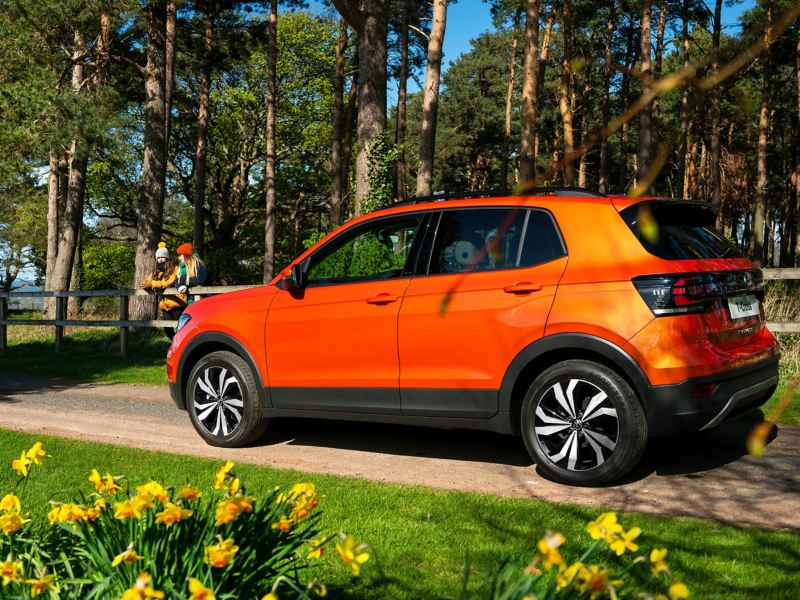 An orange T-Cross parked on a country lane 