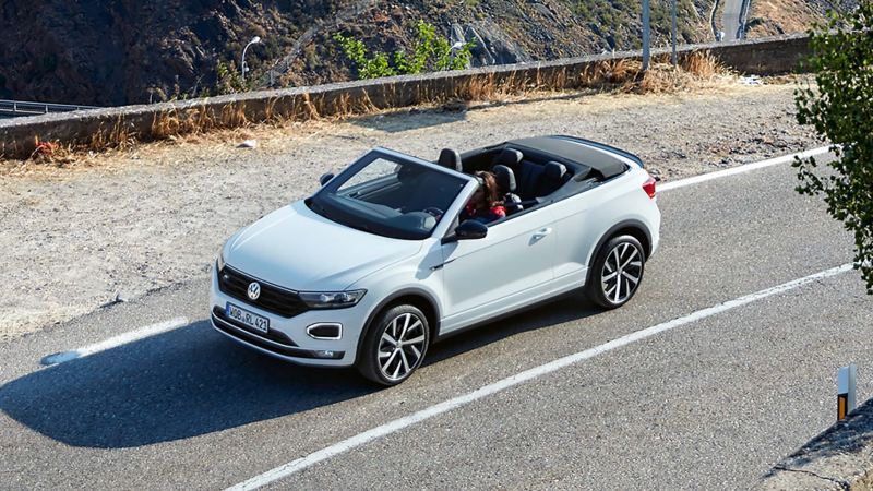 A T-Roc Cabriolet being driven down a mountain road with the roof down