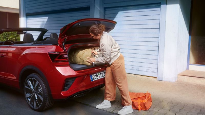Person loading boot of a red VW T-Roc Cabriolet