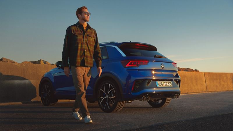The owner of a new T-Roc R from VW R with R-specific design moving away from his parked vehicle 