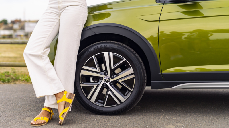 A woman leaning on a Volkswagen Taigo