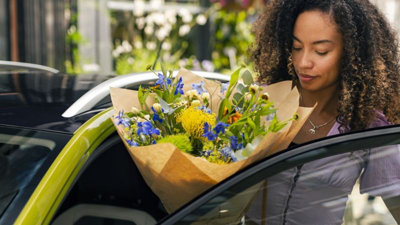 A woman holding flowers entering a Volkswagen Taigo
