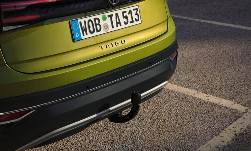 Detailed view of the optional trailer hitch at the rear of a green VW Taigo