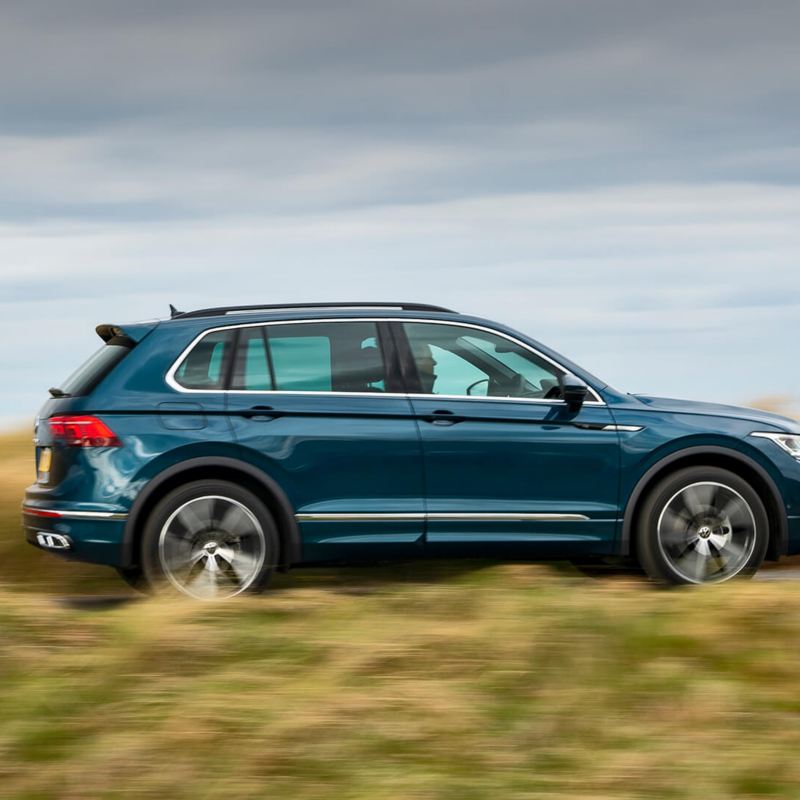 A blue Volkswagen Tiguan being driven on a country road