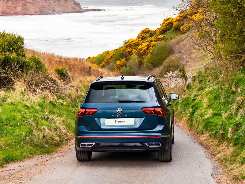 A rear shot of a blue VW Tiguan driving away into the countryside
