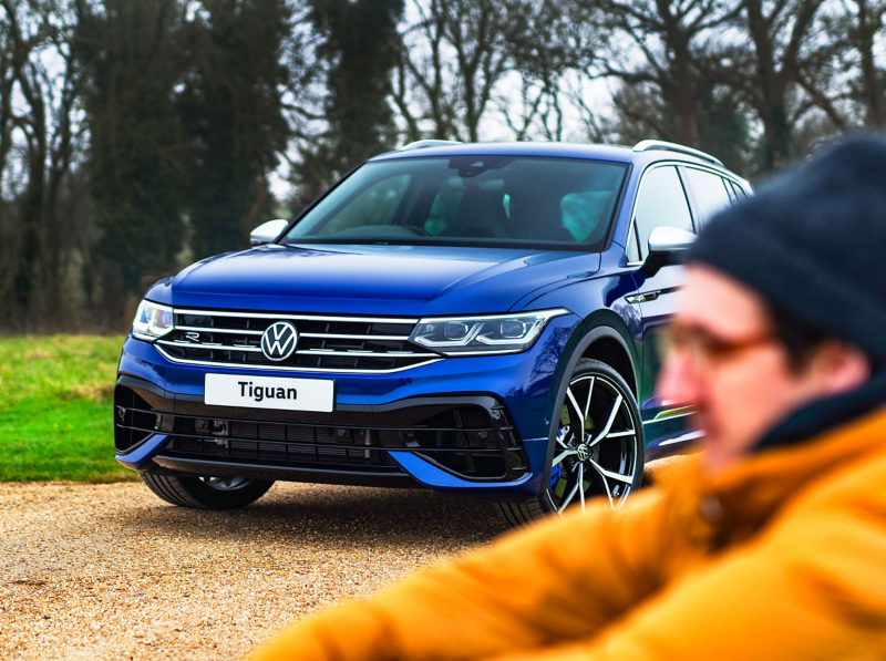 A man sitting down next to a Tiguan