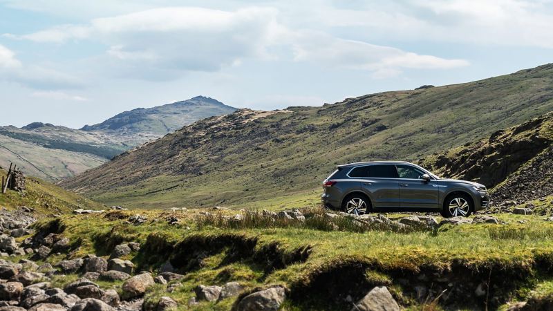 A grey Volkswagen Touareg parked in the mountains.