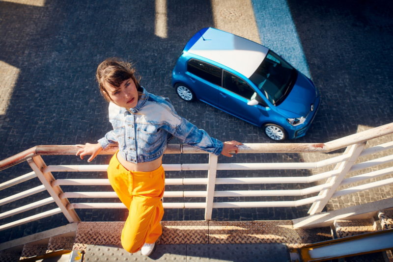 Aerial view of a parked new up! in blue with a lady standing on a balcony