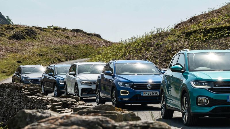 The Volkswagen SUV range, a T-Cross, a T-Roc, a Tiguan, a Tiguan Allspace, and a Touareg driving along a mountain road