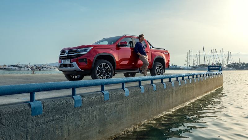 A man leaning against an Amarok with a harbour background.