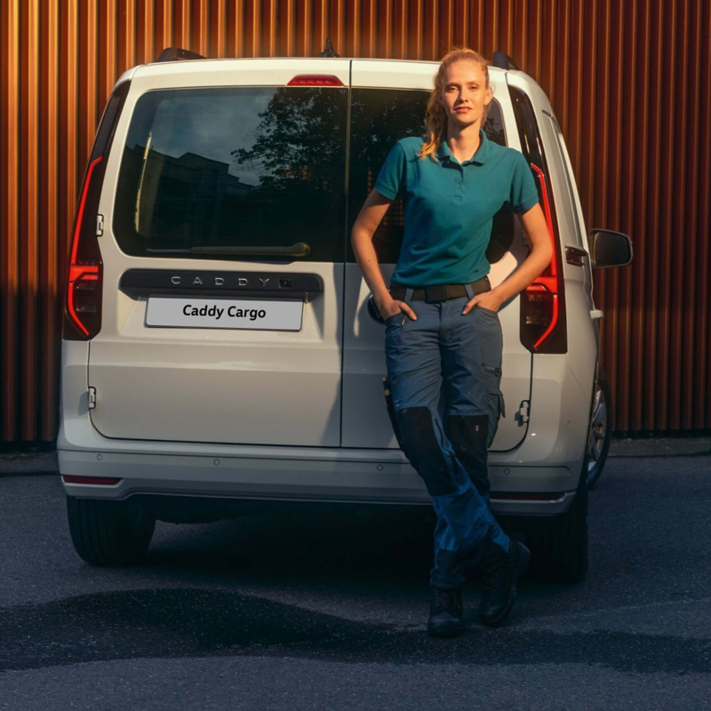 Person standing in front of a Volkswagen Caddy Cargo parked outside a building