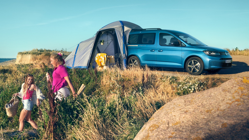 Photo showing people walking away from a Caddy California with the tent module deployed.