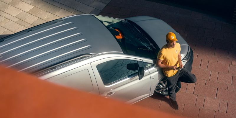 A delivery worker next to a Caddy Cargo