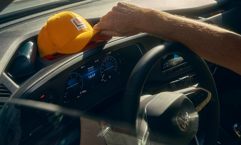 Interior photo showing a hand placing a cap onto the dashboard. 