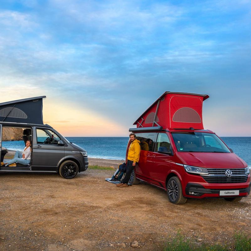 Two VW California 6.1 vans parked on a beach with their sleeping sections deployed.