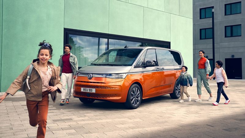 A photo of a family around a parked VW Multivan.  