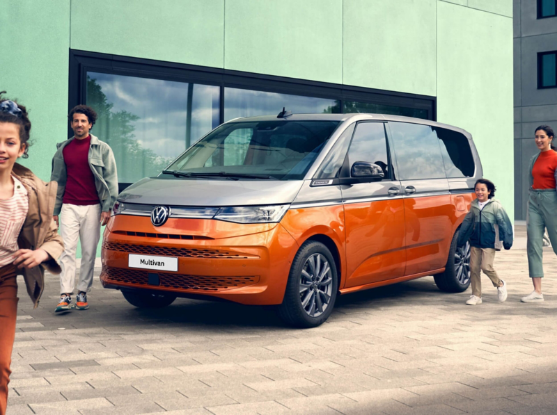 A family happily walks alongside the stationary VW Multivan