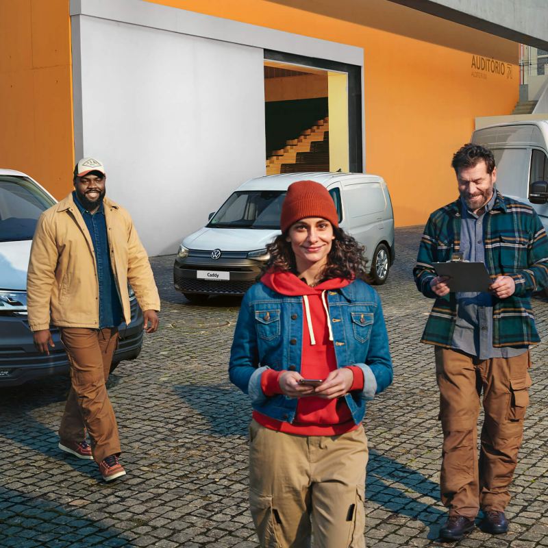 Photo showing three workers walking away from VW Vans parked at a warehouse.