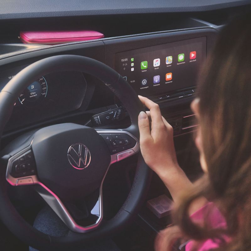 person with hand on steering wheel looking at the screen inside the new caddy