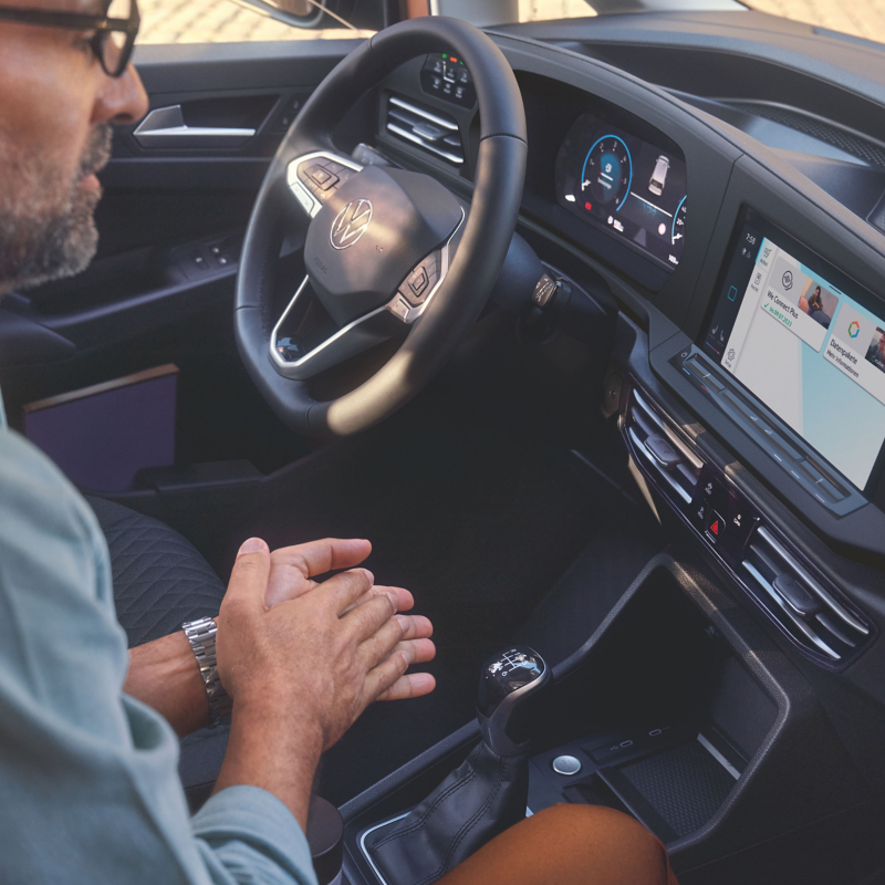 Interior of the Caddy showing a person in the cockpit using the voice control system.