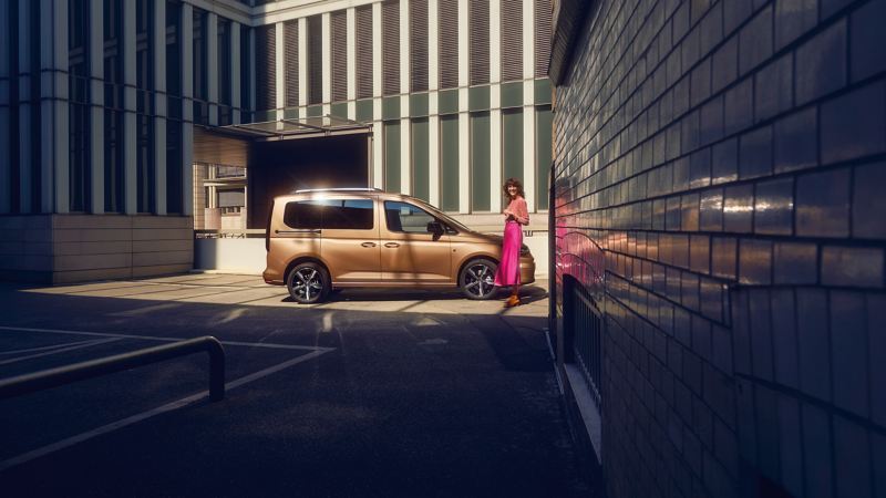 a woman wearing a pink skirt standing next to the Caddy