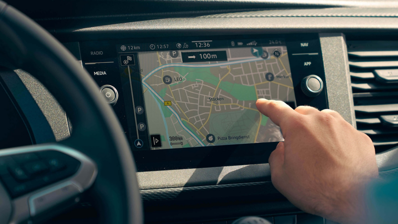 Close up of the interior dashboard of the Transporter 6.1 showing a hand using the maps app on the touchscreen module. 