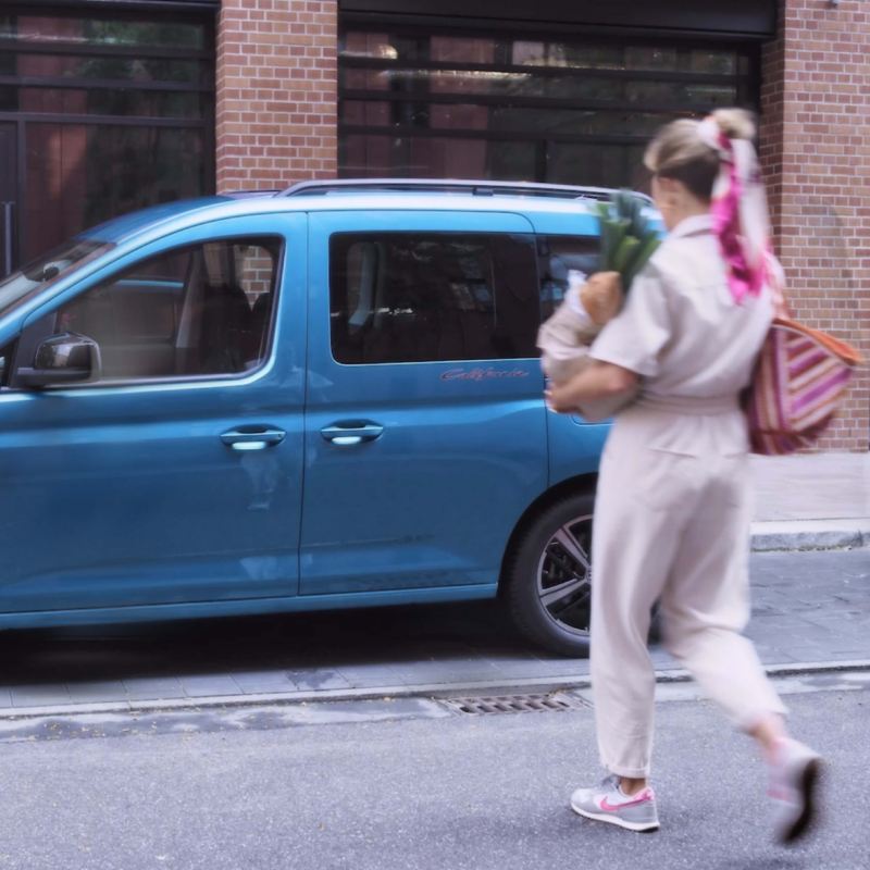 Photo of a woman taking shopping bags to a VW Caddy California.