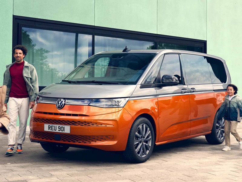 an orange multivan with a father and son walking next to it 