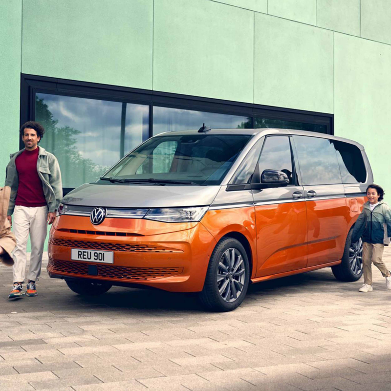 an orange multivan with a father and son walking next to it 