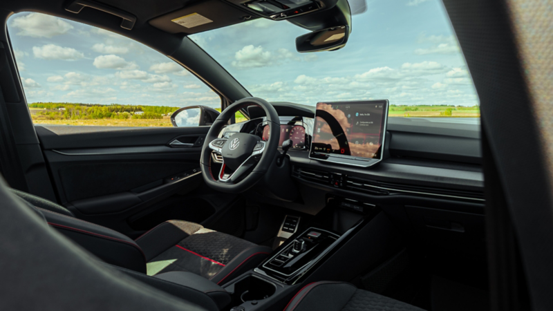 The interior of a Volkswagen vehicle showing the steering wheel, dashboard, and large touchscreen display