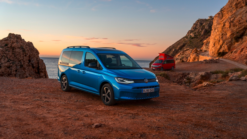 Ein VW Caddy und ein VW California stehen am Strand.