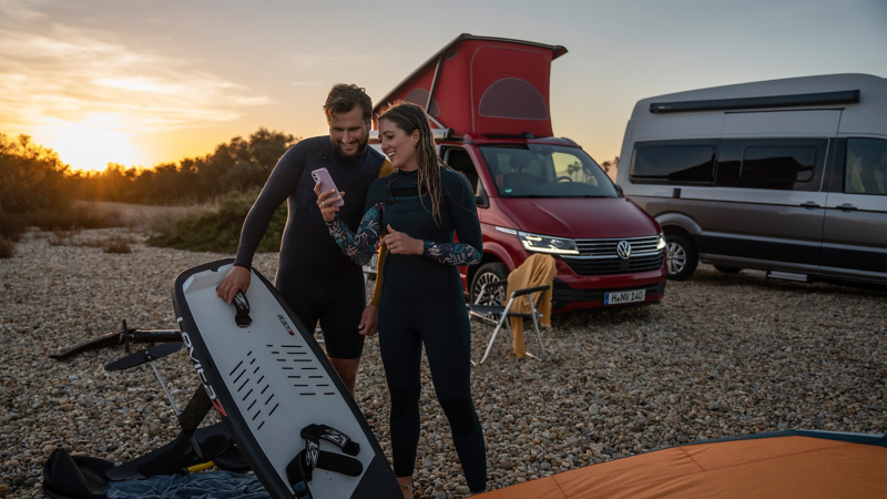 Zwei Kitesurfer blicken auf ein Smartphone.