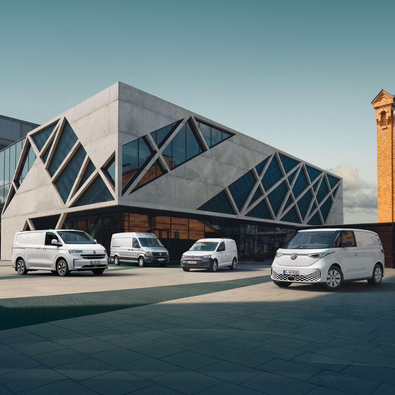 Eine Flotte von VW Nutzfahrzeugen parkt an einem modernen Gebäude.