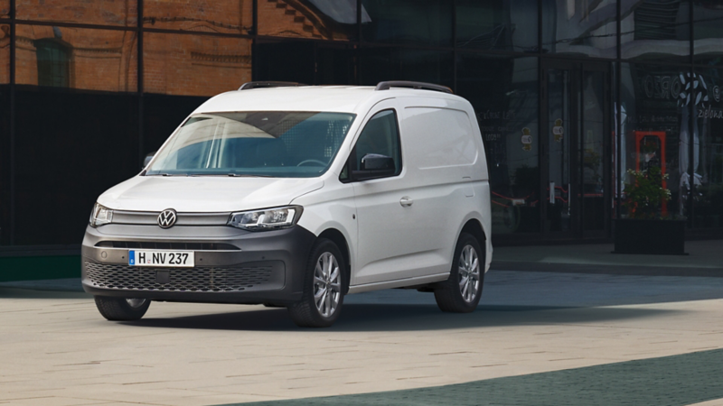VW Caddy Cargo parkt vor einem modernen Gebäude.