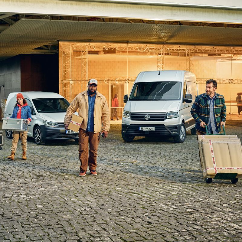 VW Transporter 6.1, VW Caddy und VW Crafter vor einem Gebäude.