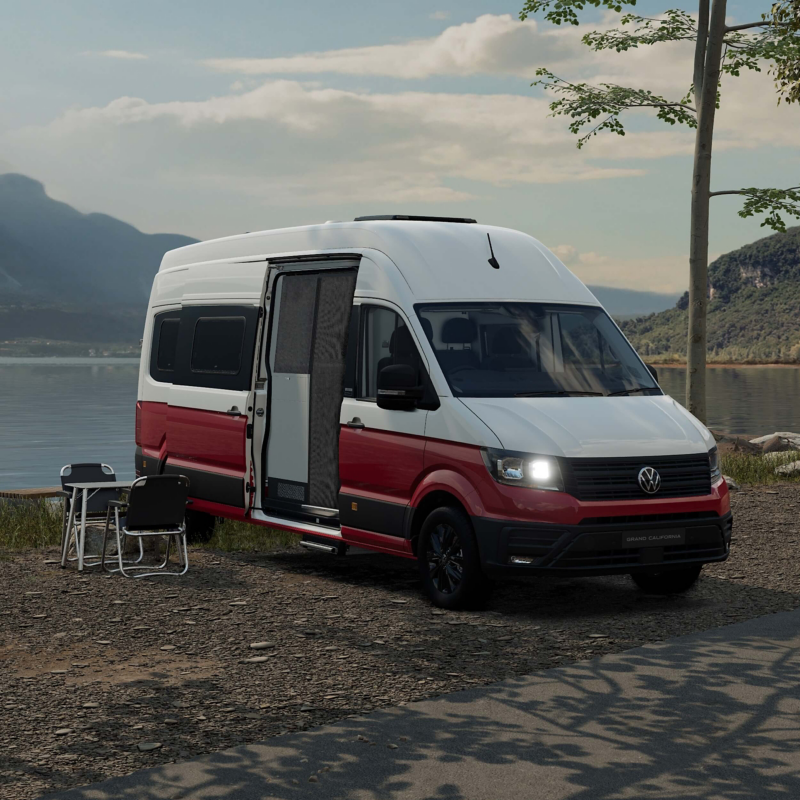 a red and white Grand California parked by the ocean with cliffs in the background