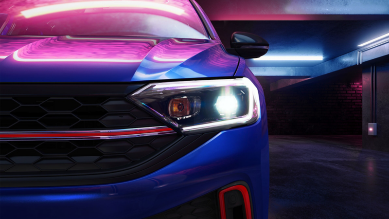 Nuevo Jetta GLI 2022 color azul iluminado por luz de neón rosa. Vista de faro LED.
