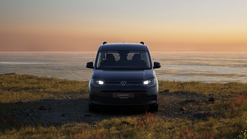a VW Caddy parked by cliffs overlooking the sea at sunset