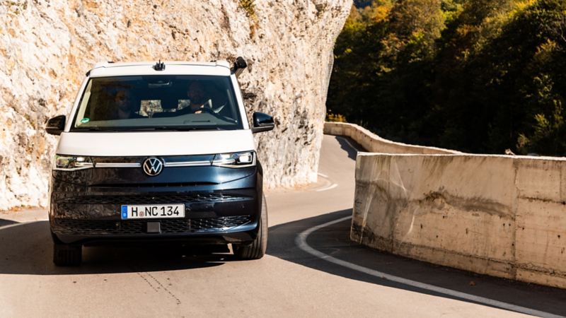 En blå och vit VW California kör på serpentinvägar