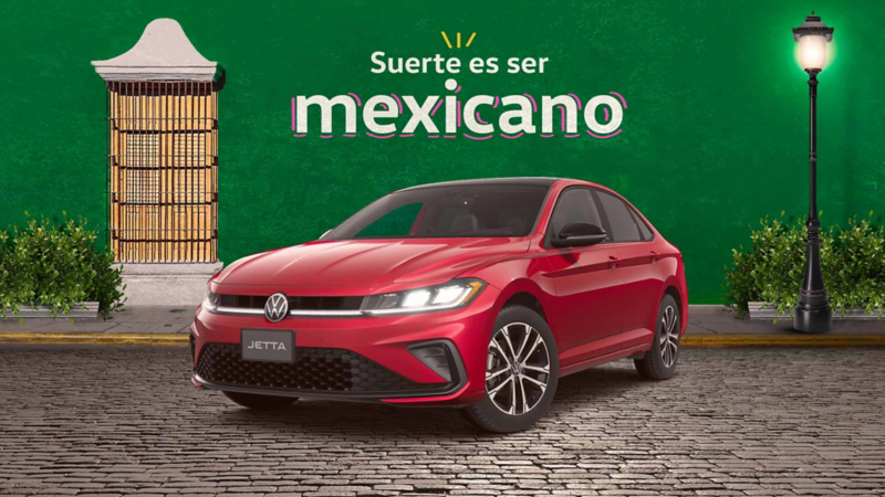 Jetta 2025 en color rojo a las afueras de un edificio colonial. Promoción de autos nuevos Volkswagen en septiembre.