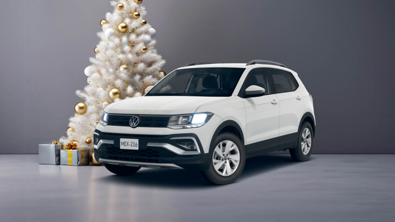 Taigun 2025 en color blanco cerca de un pino de Navidad blanco, decorado con esferas doradas y regalos al pie. 