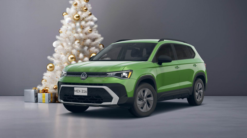 Taos 2026 en color verde cerca de un pino de Navidad blanco, decorado con esferas doradas y regalos al pie. 