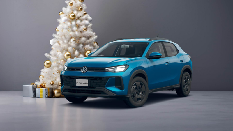 VW Tera 2026 cerca de un pino de Navidad blanco, decorado con esferas doradas y regalos al pie. 