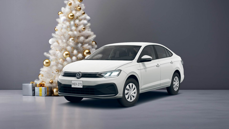Virtus 2025 en color blanco cerca de un pino de Navidad blanco, decorado con esferas doradas y regalos al pie. 