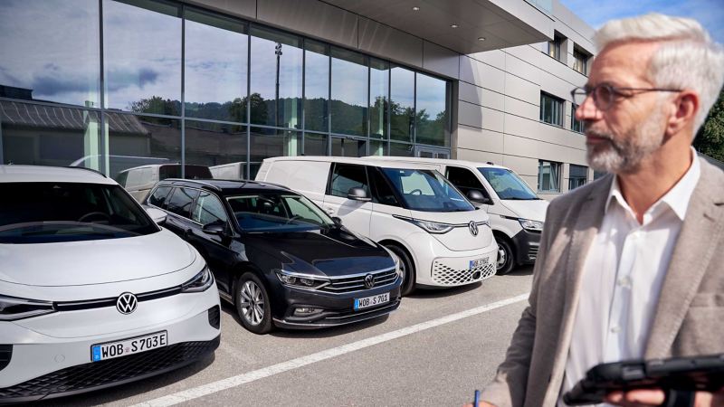 A fleet manager standing outside a Volkswagen retailer premises next to a Volkswagen Group fleet of cars and commercial vehicles