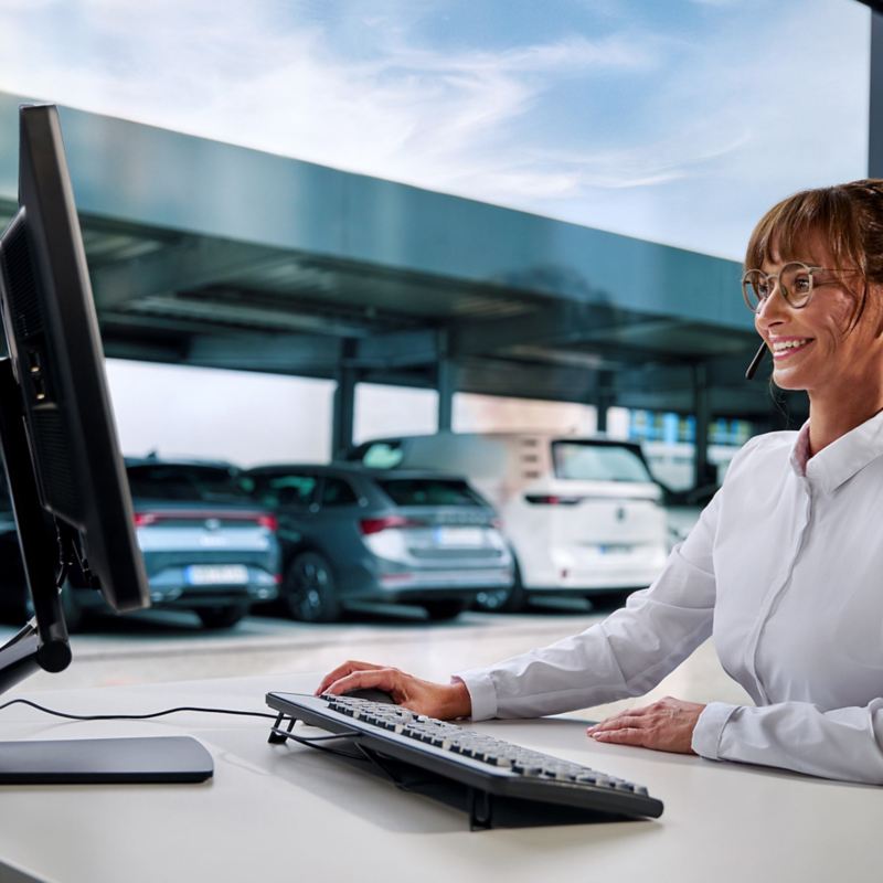 A fleet manager with a headset on with a fleet of cars in the window