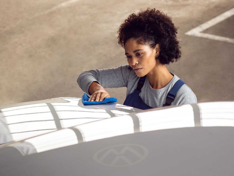 Una donna sta lucidando la carrozzeria di un veicolo con i prodotti Car Care di Volkswagen.