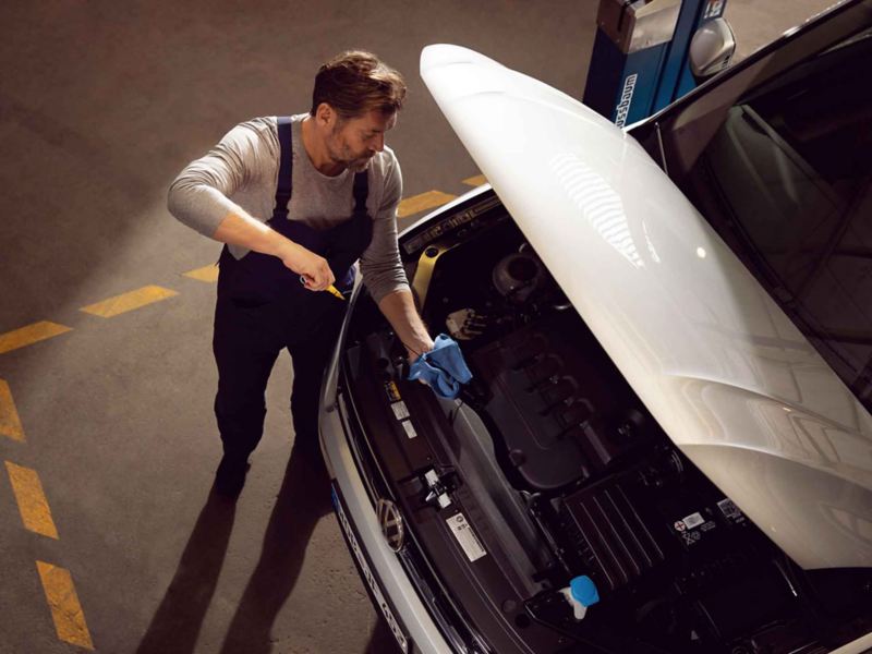Un meccanico di Volkswagen Service controlla il livello dell'olio motore di un'auto VW.