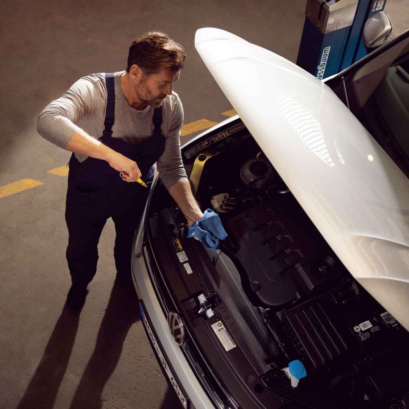 Un meccanico di Volkswagen Service controlla il livello dell'olio motore di un'auto VW.